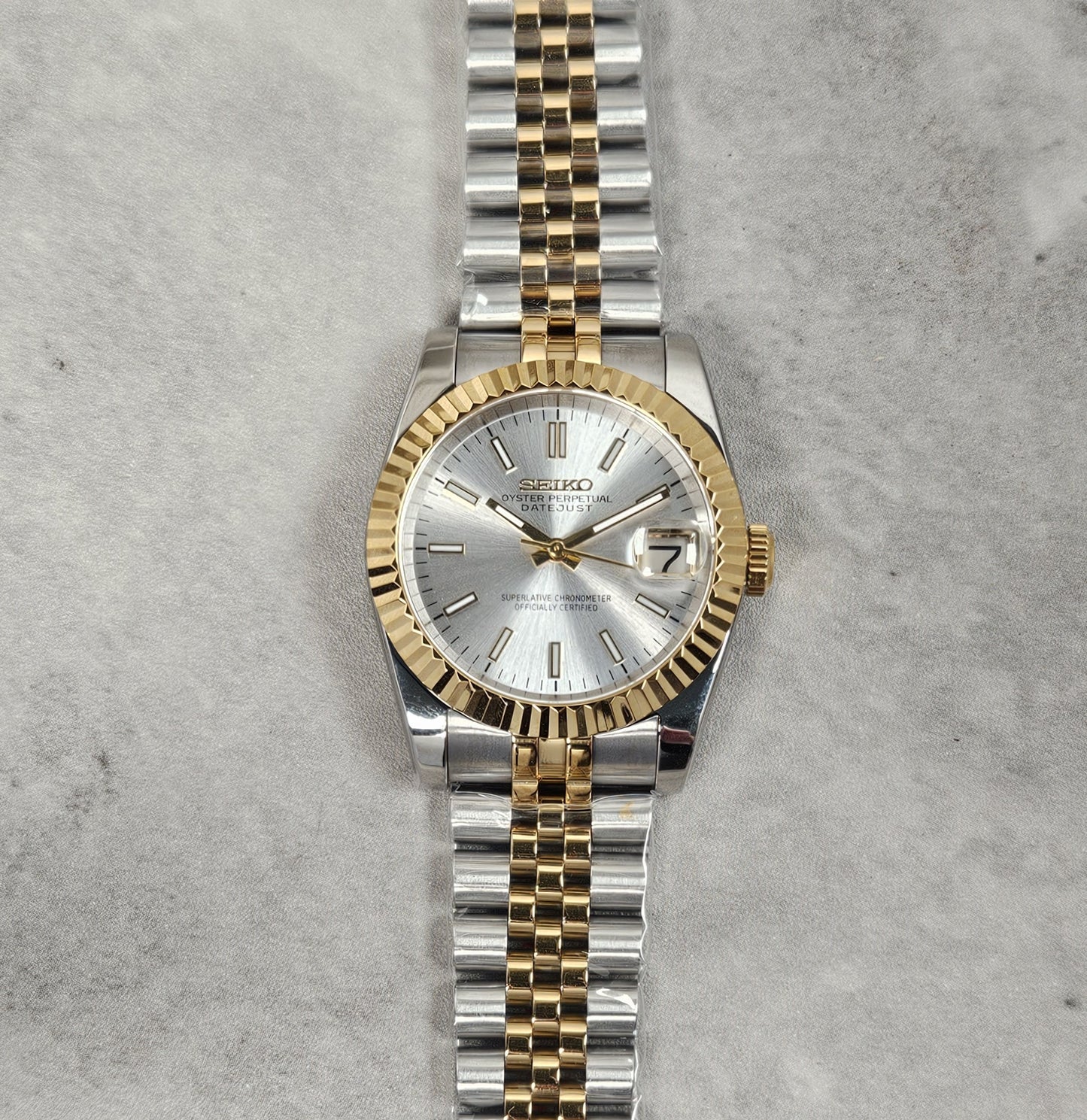 Two-tone silver and gold watch on a textured gray background