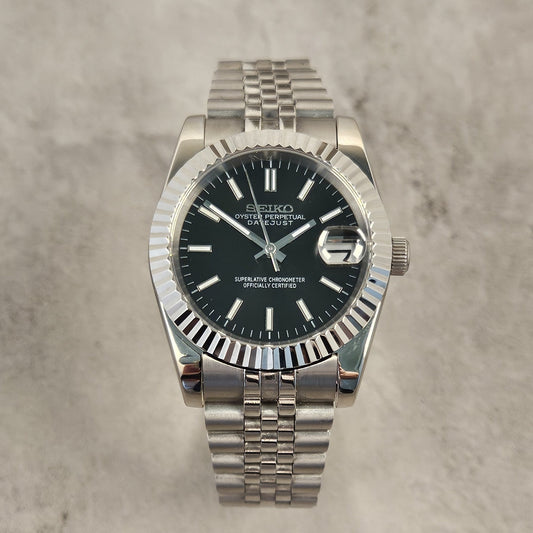 Silver Seiko watch with black dial on a gray textured background