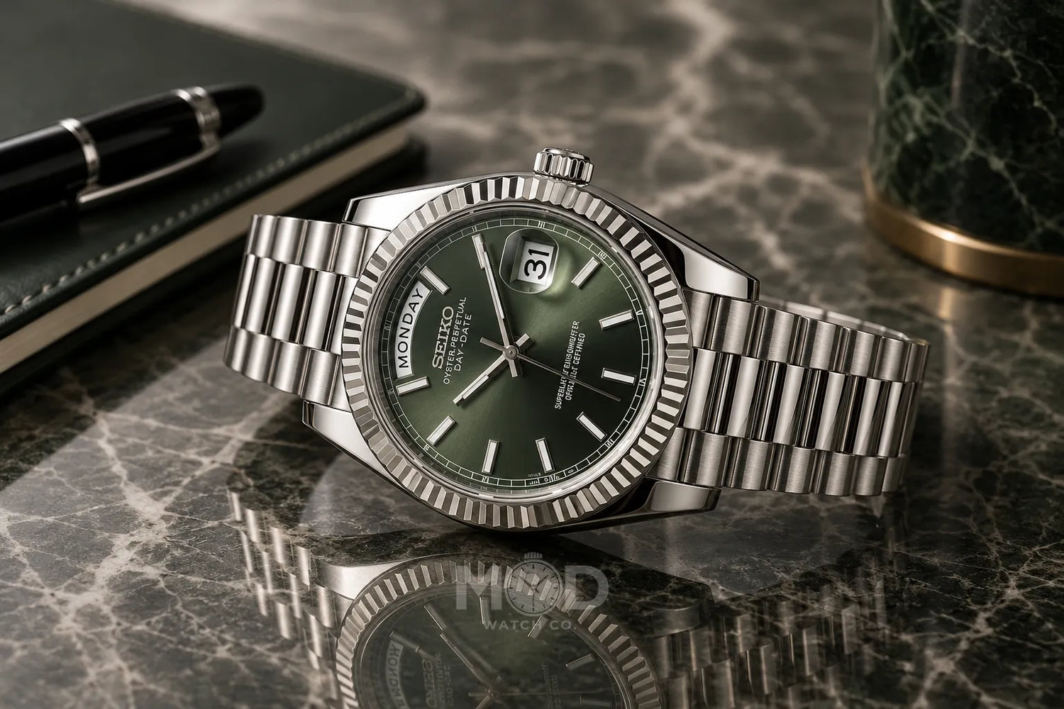 A silver stainless steel wristwatch with a fluted bezel and matching metal bracelet, featuring a dark gray dial with Roman numerals and green hands, displayed on a tennis court with a tennis racket and ball in the background.