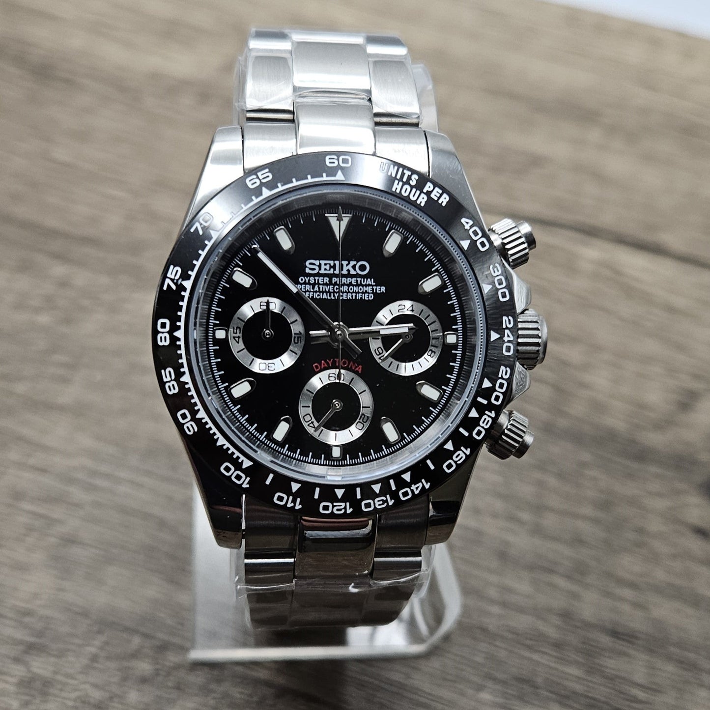 Luxury watch with black dial and silver case on a wooden surface