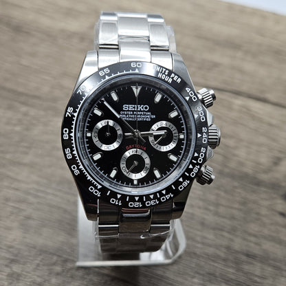 Luxury watch with black dial and silver case on a wooden surface