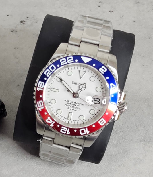 Silver watch with a red and blue bezel on a gray surface