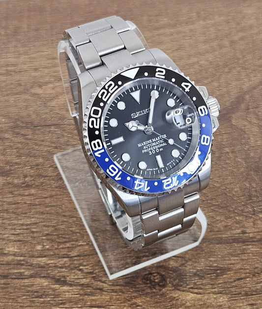 Silver watch with black and blue face on a wooden surface