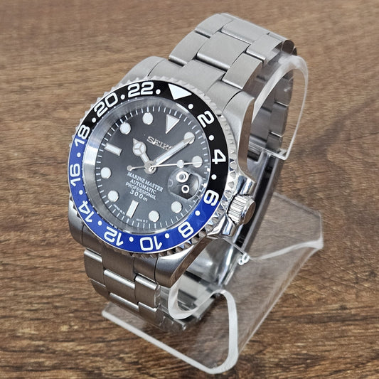 Silver watch with a black and blue bezel on a wooden surface