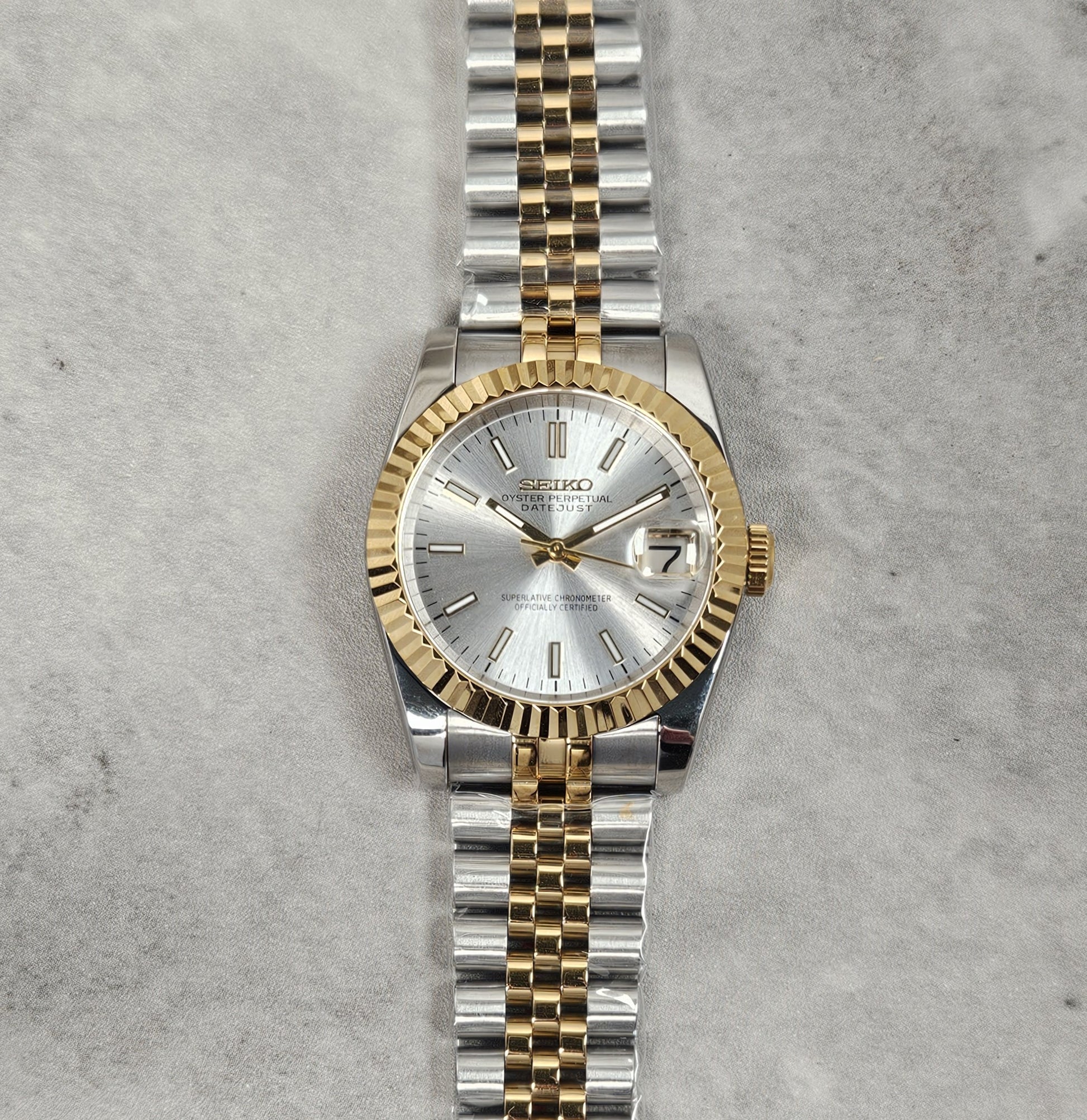 Two-tone silver and gold watch on a textured gray background