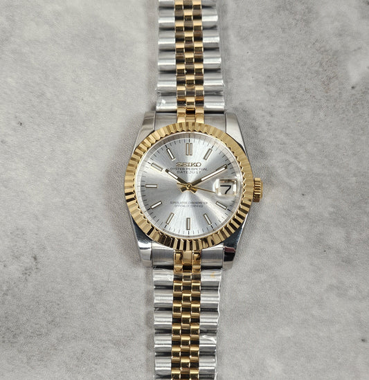 Two-tone silver and gold watch on a textured gray background