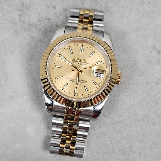 Two-tone watch with gold and silver band on a gray background