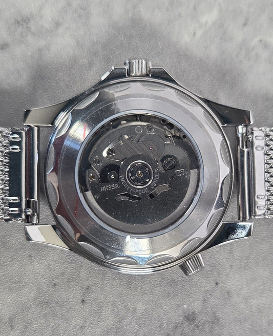 Silver watch with mesh band on a gray textured background