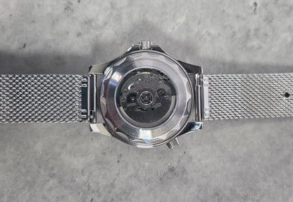 Silver watch with mesh band on a gray textured background