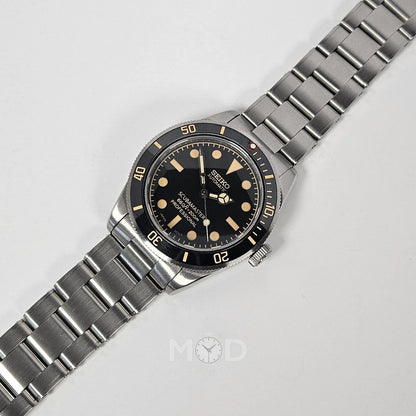 Silver wristwatch with black dial on a light gray background