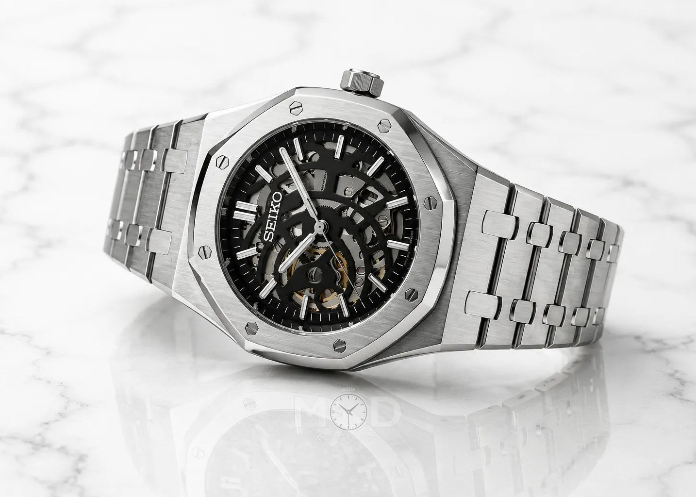 Silver Seiko watch with black face on a white marble background