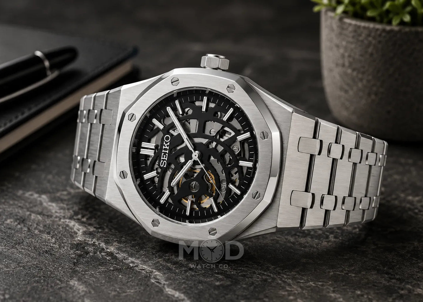 Silver Seiko watch with black face on a dark surface
