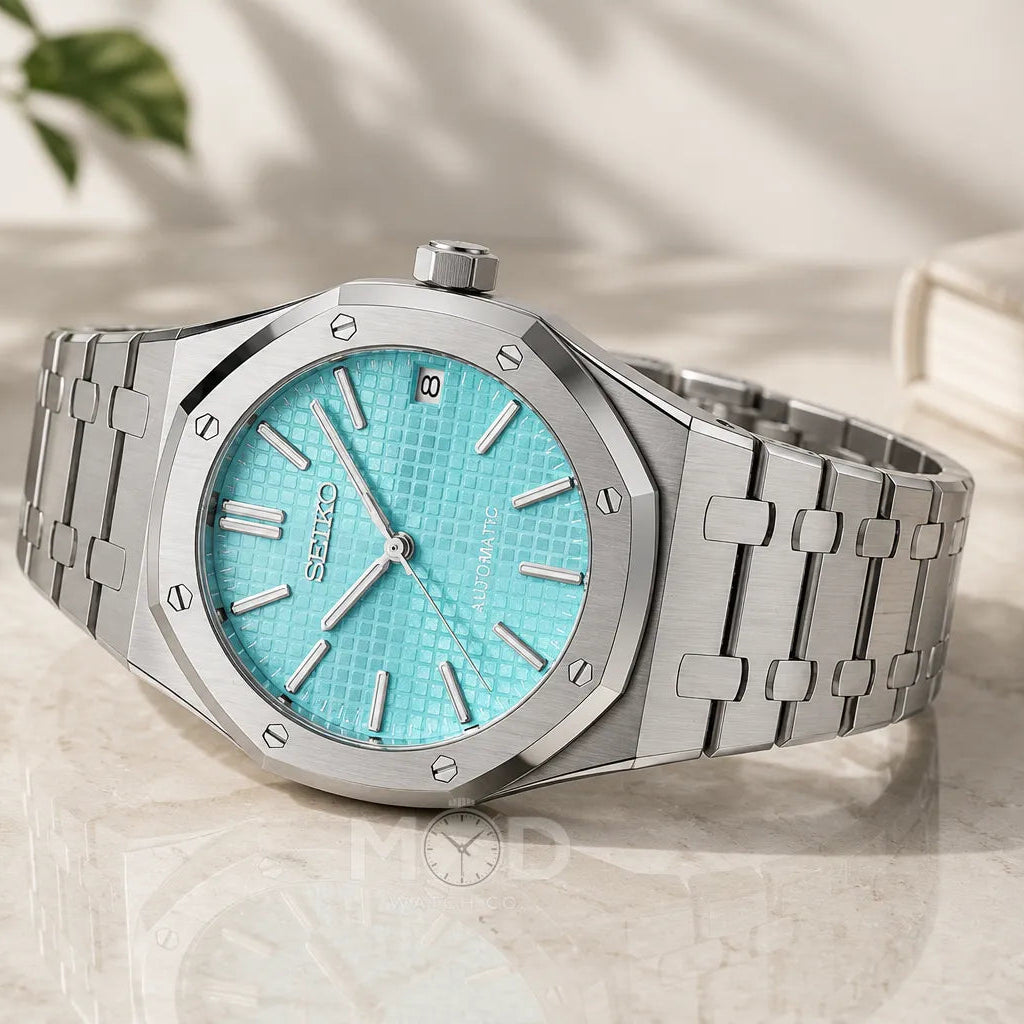 Silver watch with turquoise dial on a light surface
