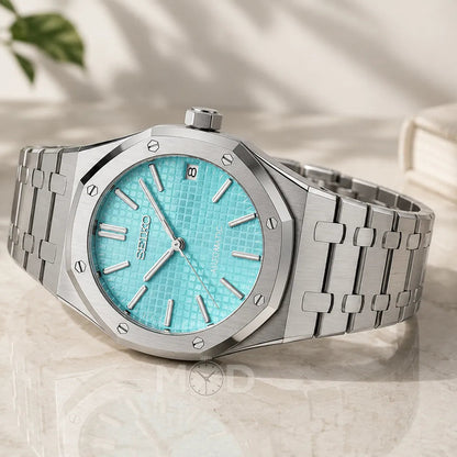 Silver watch with turquoise dial on a light surface
