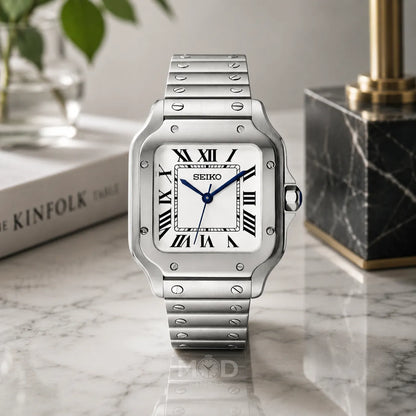 Silver Seiko watch on a marble surface with a book and decorative item in the background