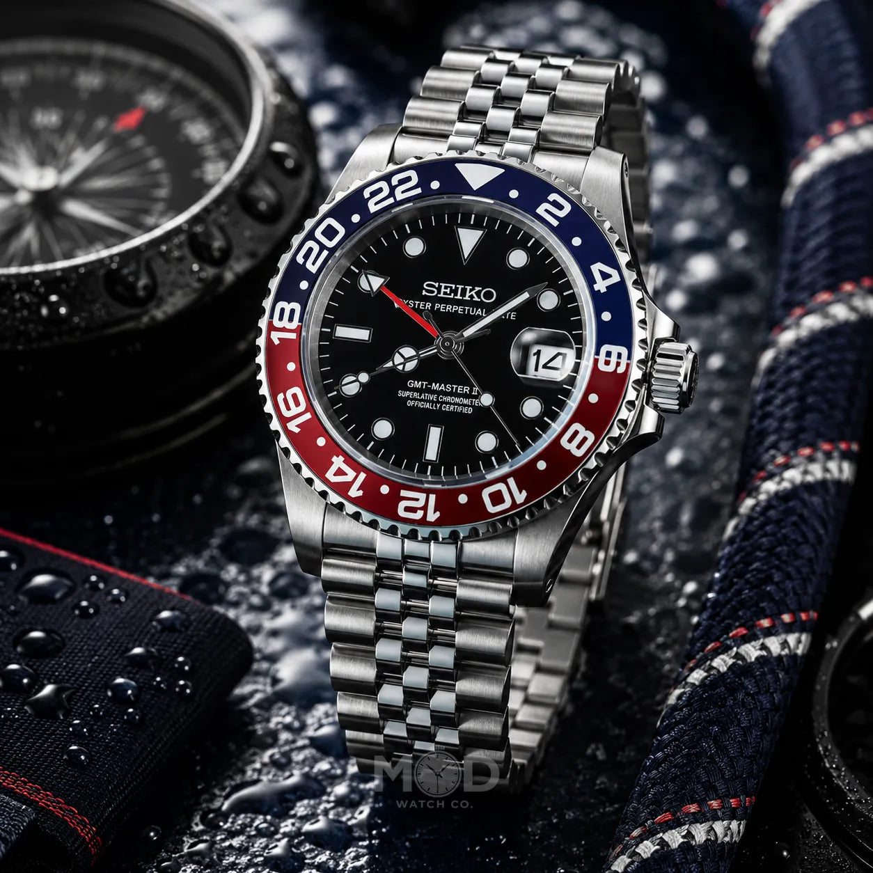 Seiko watch with a silver bracelet and red and blue bezel on a textured surface.