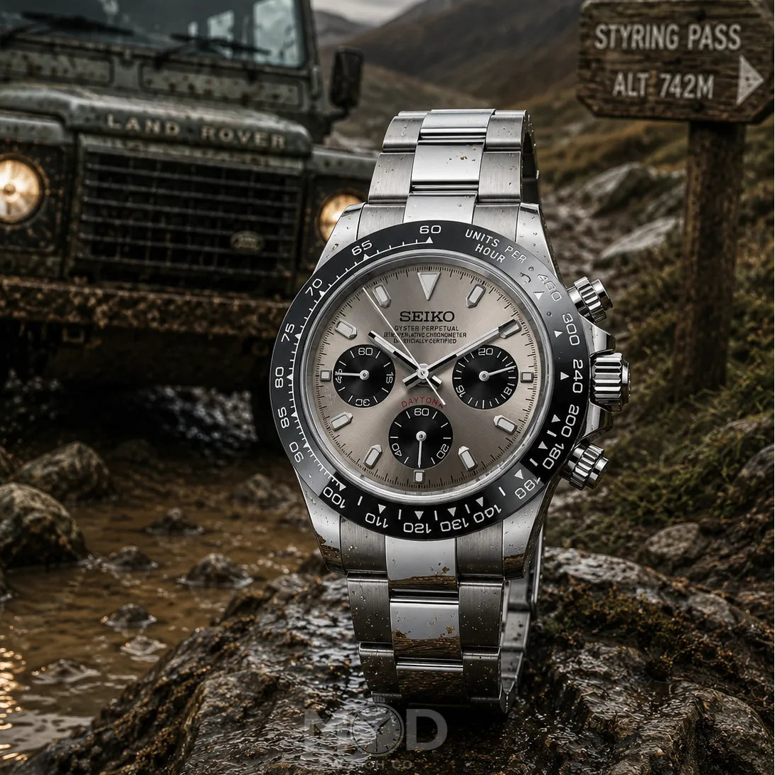 Silver Seiko watch on a rock with a Land Rover and mountainous background