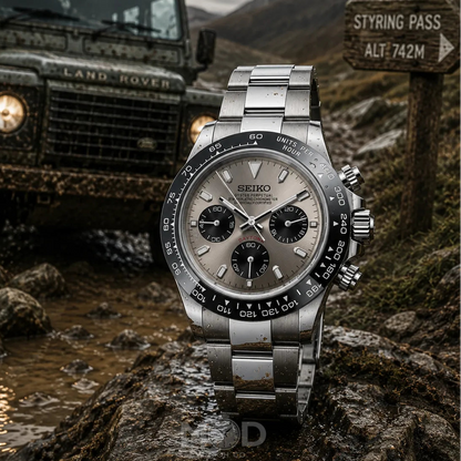 Silver Seiko watch on a rock with a Land Rover and mountainous background