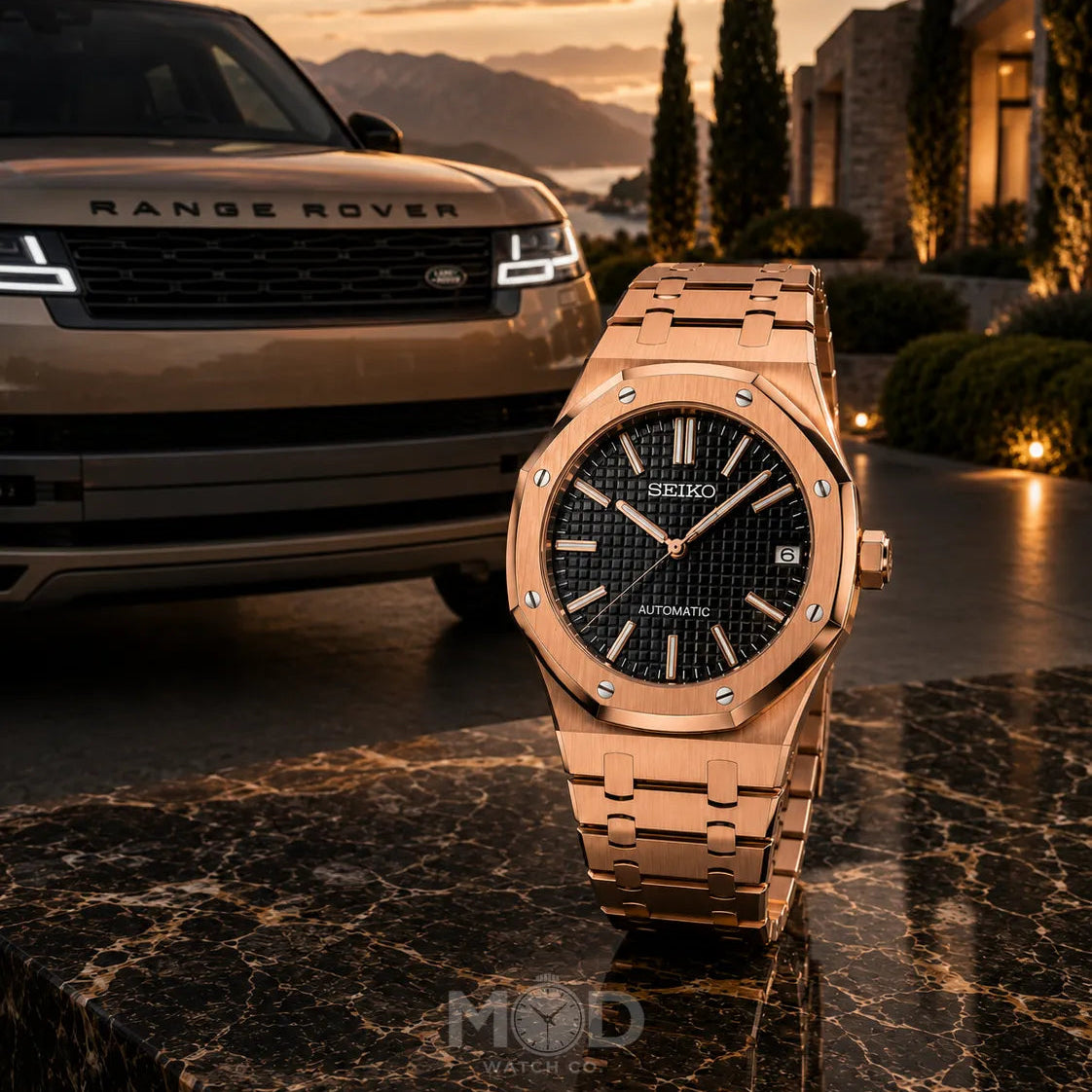 Rose gold watch in front of a Range Rover with a sunset background