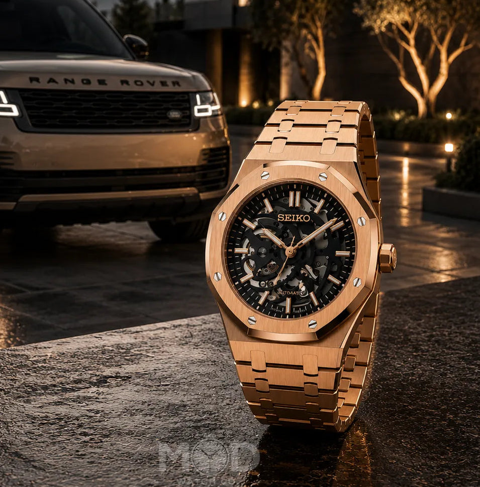 Rose gold watch in front of a Range Rover with a sunset and modern building in the background