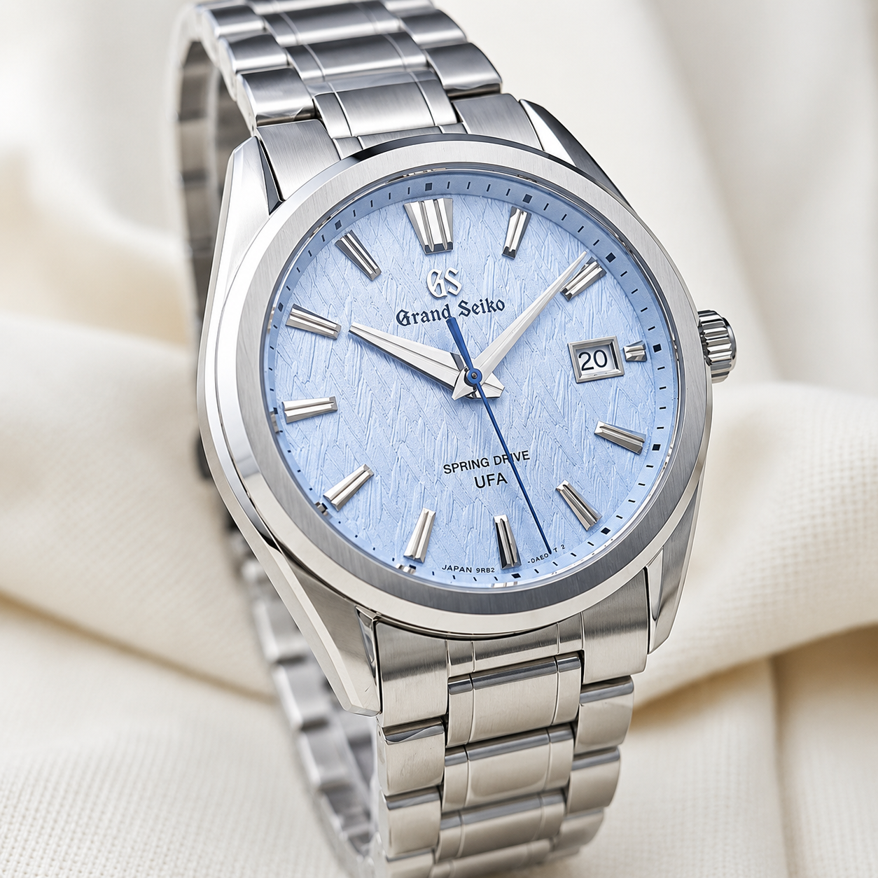 Grand Seiko watch with silver metal strap and blue dial on a light background