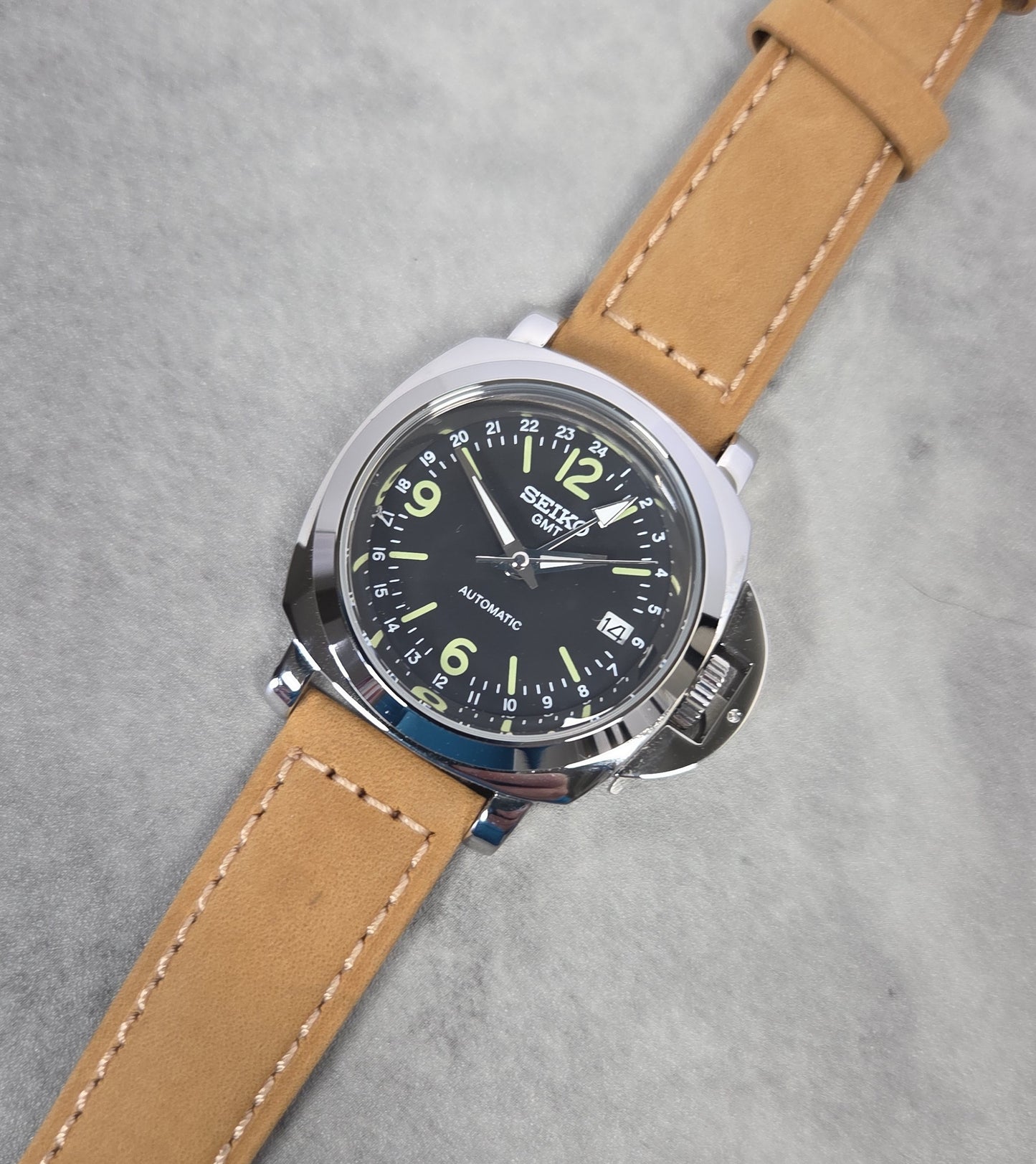 Wristwatch with brown leather strap and black dial on a gray background