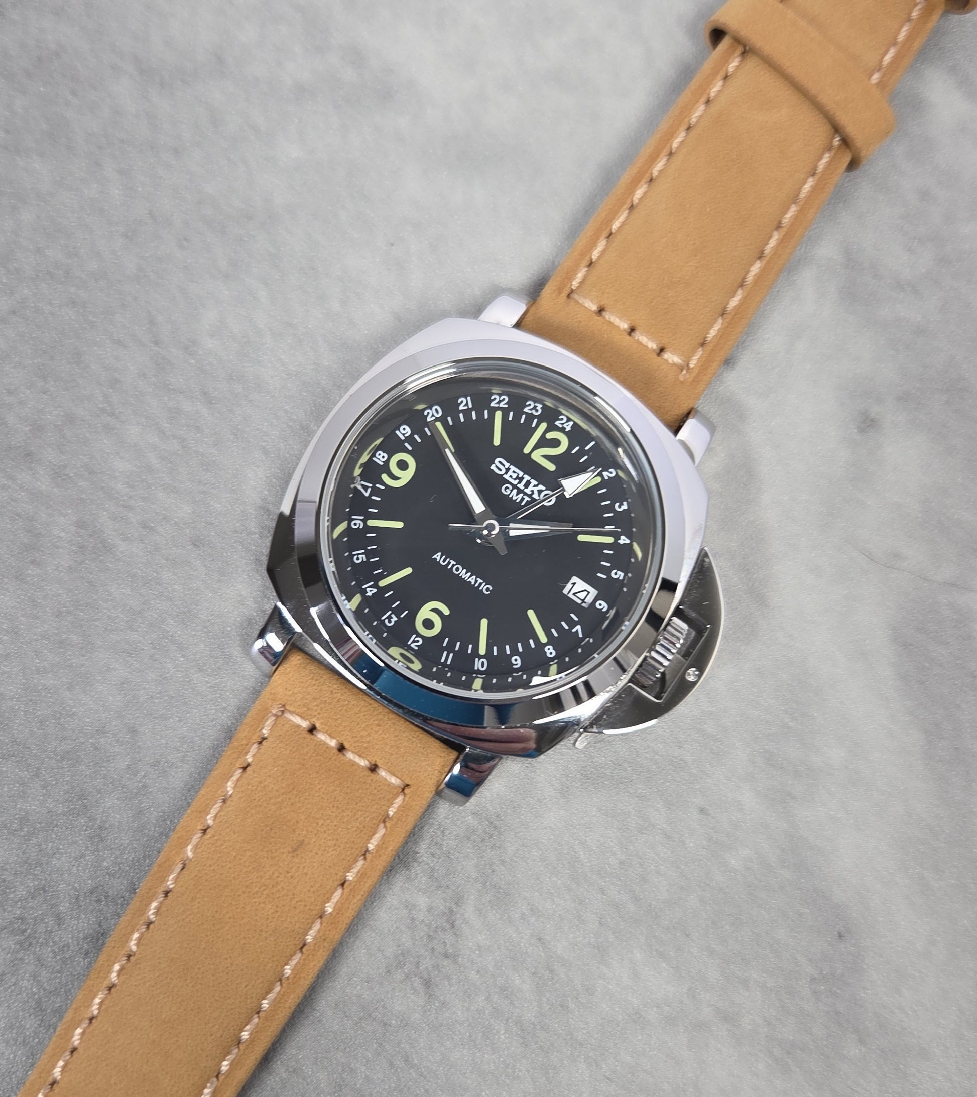 Wristwatch with brown leather strap and black dial on a gray background