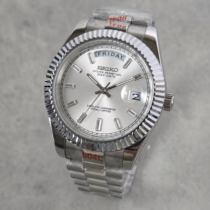 A Seiko Day-Specific wristwatch with a silver-tone stainless steel fluted bezel, silver dial, and matching steel link bracelet, shown on a light gray textured background.