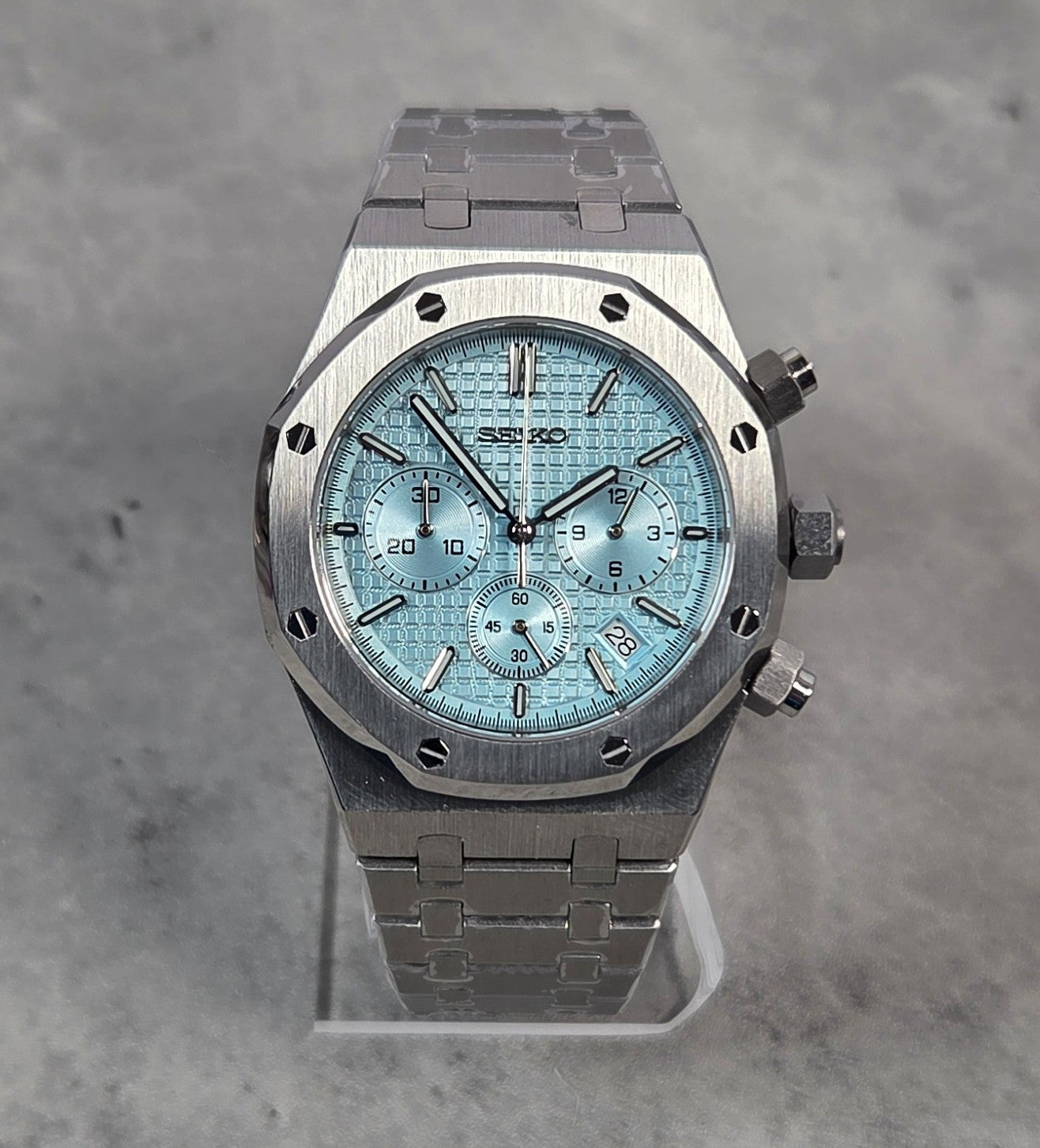 Luxury watch with a blue face and silver case on a gray background