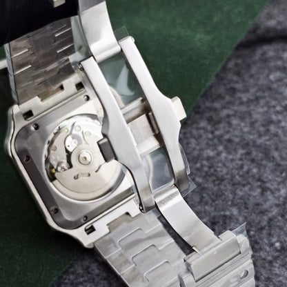 Close-up of a silver watch with a visible mechanical movement on a textured surface.